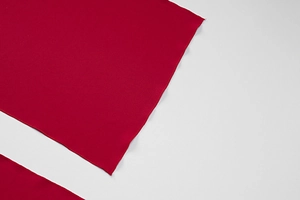 Detailed close-up showing the precise overlock edge stitching on red fabric texture