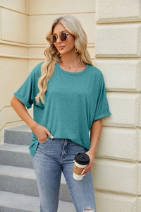 Detail of rolled cuffs on an oversized teal crew neck t-shirt paired with denim jeans