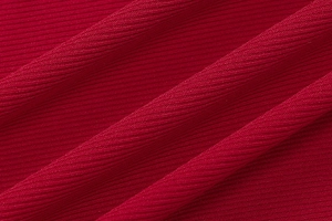 Macro shot of vertical ribbed texture and soft drape of dark red knitted fabric