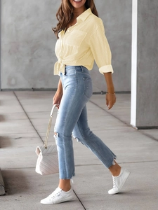 Detail view of yellow striped shirt with front knot hem and distressed skinny blue denim jeans
