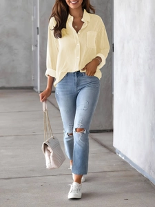 Detail of loose striped yellow shirt with blue distressed jeans and quilted chain bag