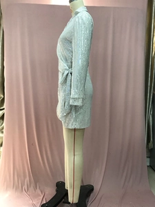 Detail of white sequin cocktail dress featuring a V-neck wrap design and waist tie belt