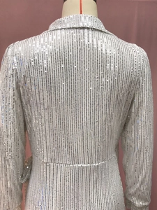 Macro shot of silver sequins on long sleeve dress with reflective metallic texture