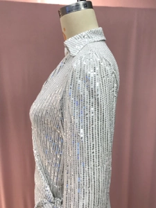 Detailed view of silver sequin fabric texture on a long-sleeved evening gown bodice