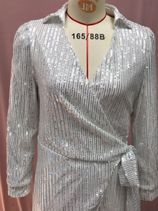 Detail of white sequin wrap dress with V-neckline and belted waist on a mannequin