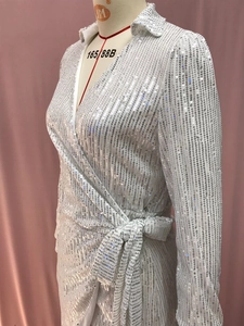 Detailed view of silver sequin wrap dress with V-neck, waist tie and long sleeves
