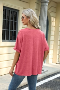 Detail of coral pink loose fit T-shirt with rolled sleeves and round neck on a model