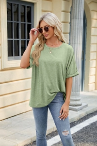 Close-up of sage green knit fabric texture and cuffed sleeves on a loose women's t-shirt