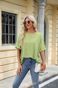 Detail of grass green cotton t-shirt with rolled cuffs and natural textured fabric