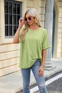 Detail of avocado green loose fit t-shirt featuring rolled cuffs and crew neck on a model