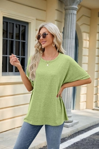 Detail of the light green loose-fit T-shirt showing drop shoulder and crew neck design