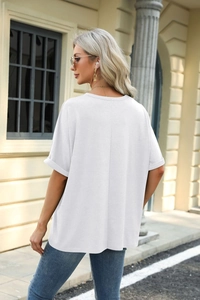 Close-up of a white oversized T-shirt showing detailed rolled cuffs and soft fabric texture
