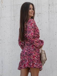 Détail de robe mini fleurie avec manches lanternes et ourlet à volants sur mur gris