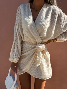 Détail d'une robe courte crème col V avec manches bouffantes et taille nouée élégante