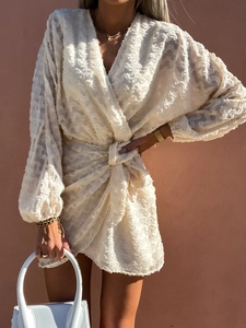 Détail de la robe mini blanche à texture frangée, col en V et manches bouffantes
