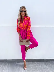 Detail of high-waist pink trousers with a bow tie belt and floral shirt matching