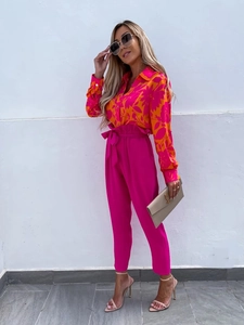 Detail of high-waist magenta trousers with a bow tie and floral print long sleeve shirt