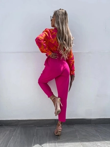 Close-up of bright pink high-waisted slim trousers and colorful printed long sleeve shirt