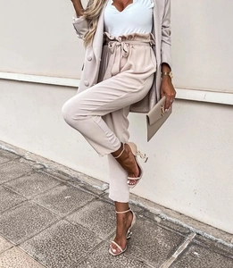 Detail of high-waist paperbag trousers with tie belt and pleats in light beige