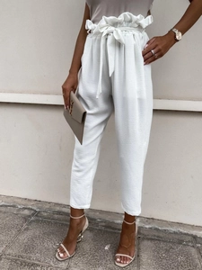 Close-up of high-waist white trousers with vertical pleats and matching tie belt
