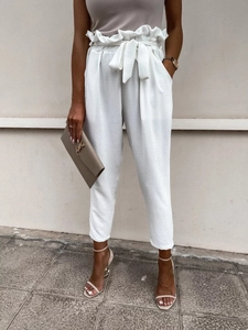 Detail of white high-waisted paperbag trousers with elegant tie waist and fabric texture