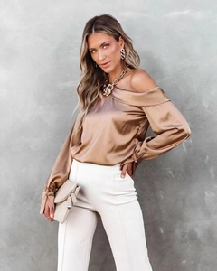 Detail of elegant champagne satin blouse with off-shoulder neckline and silky finish