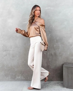 Detailed side view of champagne satin off-shoulder long sleeve top and white trousers