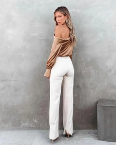 Detail view of champagne satin off-shoulder blouse with lantern sleeves and white trousers