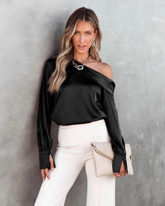 Detailed view of black satin off-shoulder blouse with slit button cuffs and glossy texture