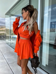 Détail d'un ensemble de loisirs orange vif trois pièces avec gilet, short et chemise