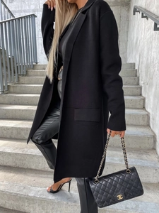 Dettaglio di un cappotto nero di media lunghezza con revers classici e tasche laterali