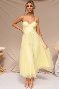 Detail of light yellow tulle dress featuring fine pleated neckline and layered mesh skirt