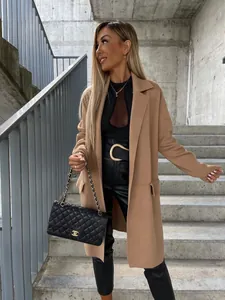 Dettaglio di un cappotto di lana cammello con pantaloni in pelle e borsa a catena