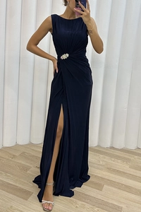 Detail of navy sleeveless pleated dress featuring a high slit and rhinestone flower brooch