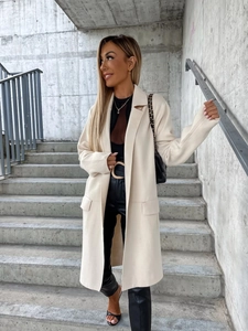 Dettaglio di un cappotto lungo in lana crema con revers classici e tasche a patta