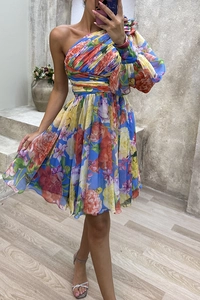Close-up of vibrant floral print dress showing the single puff sleeve and waist pleats