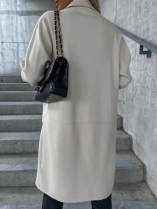Vista posteriore di un cappotto lungo di lana beige con vestibilità ampia e drappeggio