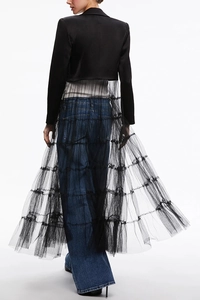 Detail showing layers of a black satin blazer and tiered sheer mesh skirt on a model