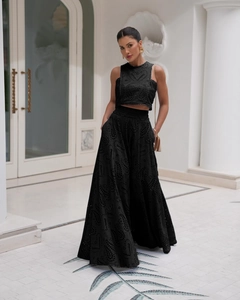 Dettaglio del ricamo in pizzo nero su un crop top senza maniche e pantaloni a gamba larga