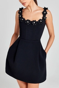 Close-up of black A-line dress featuring 3D floral appliqués with white bead centers