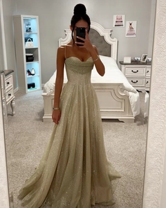 Détail d'une robe longue à paillettes dorées avec fines bretelles et taille corsetée