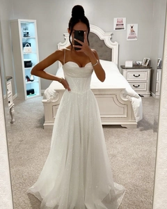 Détail de la robe corset à paillettes blanches avec fines bretelles et jupe évasée trapèze