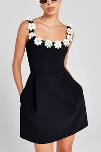 Close-up of black mini dress featuring white 3D floral appliques and functional side pockets