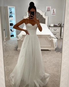 Gros plan sur une robe de bal blanche à paillettes avec taille ajustée et jupe longue brillante