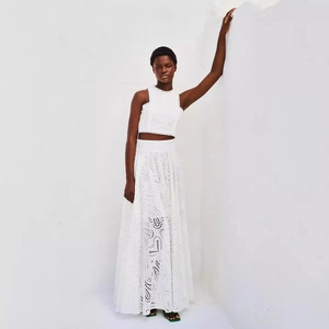 Elegante set due pezzi bianco con crop top in pizzo senza maniche e gonna lunga a vita alta