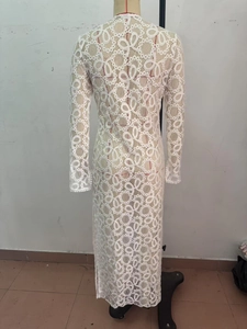 Dettaglio dei motivi in pizzo traforato su questo abito lungo bianco a maniche lunghe