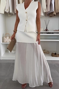 Dettaglio del gilet bianco con bottoni dorati e gonna in tulle a strati per un look estivo
