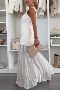 Dettaglio dell'elegante gilet bianco in maglia e gonna a pieghe per uno stile da resort