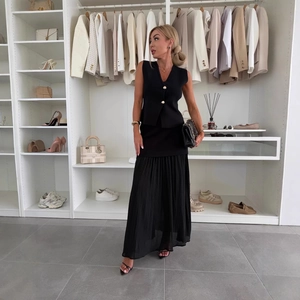 Completo minimalista nero con gilet in maglia scollo a V e gonna lunga a pieghe a vita alta