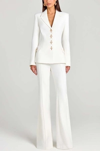 Detail of white women's suit featuring gold star-shaped buttons and pleated trousers